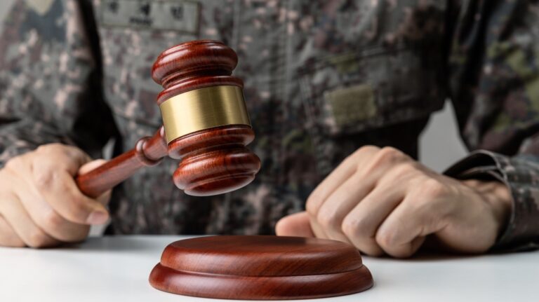 Hand of soldier holding gavel at courtroom